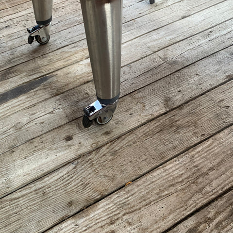 Grijze prototype wheelkit voor Everdure 4K & K1 barbecues, met zilverkleurige wielen op houten vlonder.