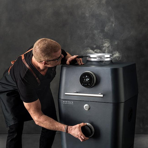 Man bedient de Everdure 4K kamado in mat zwart met touchscreen en rookafvoer.