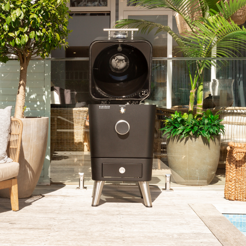 Everdure 4K Mat Zwart kamado grill met open deksel, touchscreen en RVS poten op een terras.